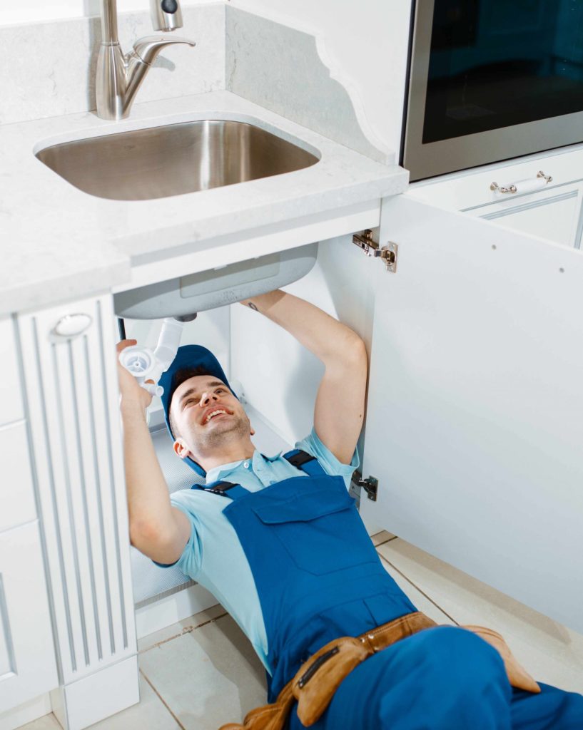 male-plumber-in-uniform-installing-drain-pipe-JF85MSE-scaled.jpg